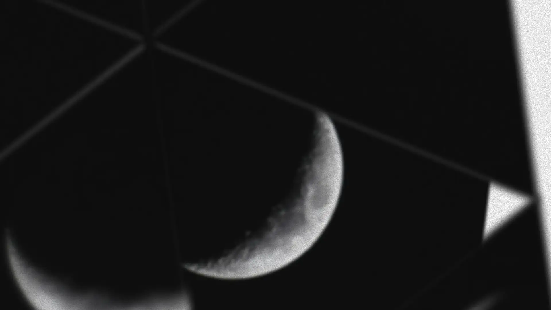 A black and white photo of a crescent moon with angular geometric lines crossing the dark sky.